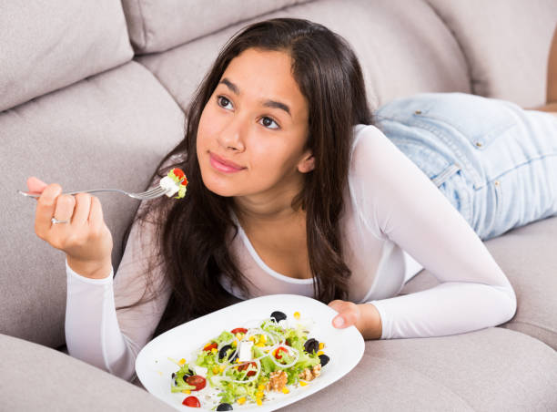 istock Positive young female eating salad 959262346
