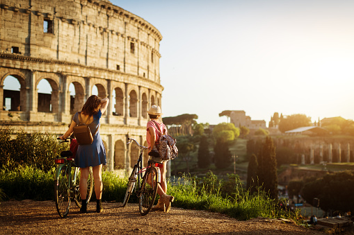 Tourist women in Rome: by the Coliseum.\nThe red guide book is a stunt fake guide made with my own pictures. PR attached.