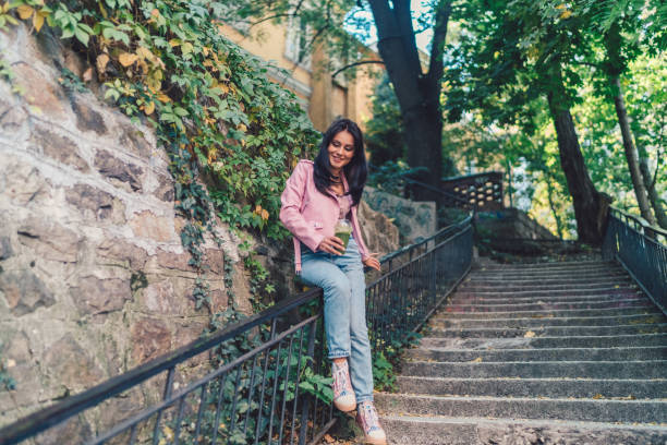 Smiling woman in the park dieting with detox smoothie Young woman with vegetable cocktail moving downstairs sliding down stock pictures, royalty-free photos & images