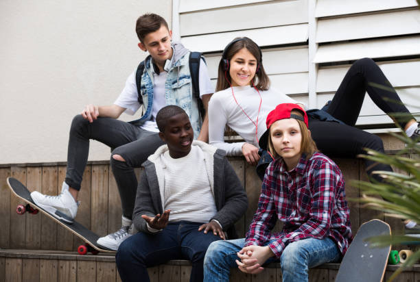 istock girl and three boys hanging out outdoors and discussing something 959270480