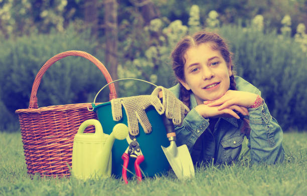 istock female with gardening tools while lying in park 959274920