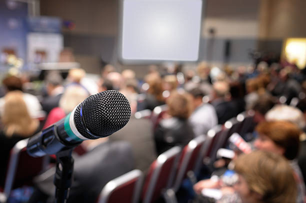 istock Close-up of a microphone at a full conference hall 95928275