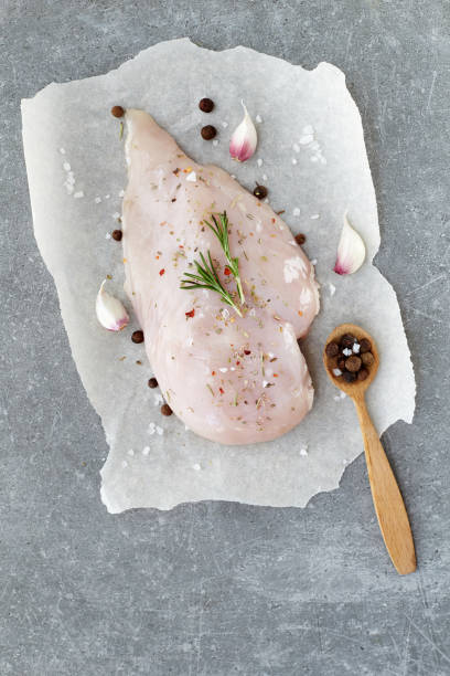 raw chicken breast with spices, garlic and rosemary on a grey stone table. top view. - garlic chicken breast raw chicken imagens e fotografias de stock