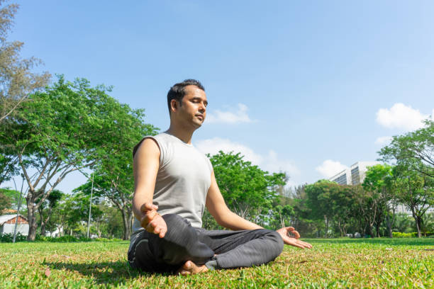 istock Indian man meditating in lotus pose outdoors on summer lawn 959287614