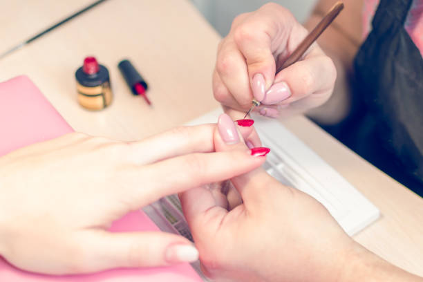 istock Manicurist paints nails with red lacquer in the salon 959295512