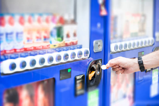 Hand inserting Japanese Yen into a vending machine in Tokyo the capital of Japan.