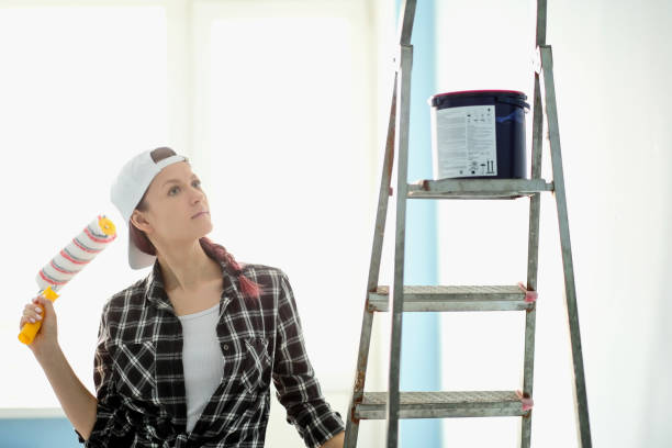 istock Girl painter, designer and worker paints a roller and brush the wall 959309192