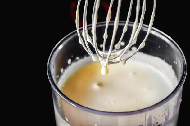 istock Metal whisk for whipping eggs with cream and drops on a dark background. 959312010