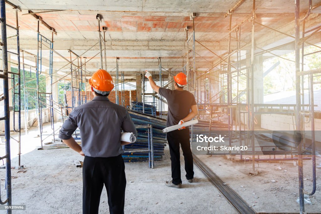 Engineer discussing with foreman about project in building construction site Construction Industry Stock Photo
