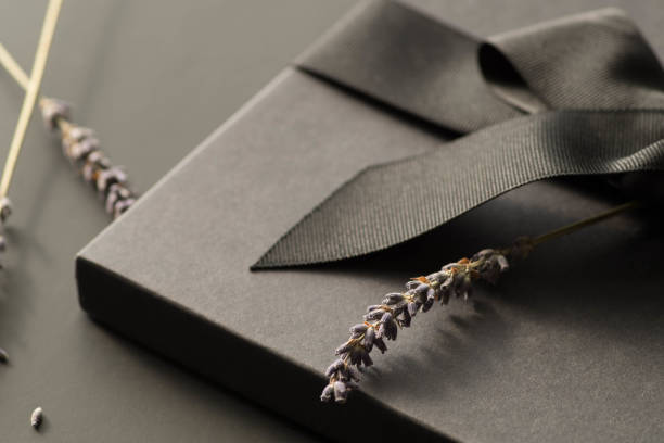 istock Black gift box on a dark contrasted background, decorated with a textured bow and feathers, creating a romantic atmosphere. Typically used for birthday, anniversary presents, gift cards, post cards. 959323674