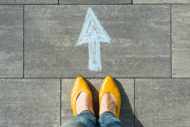 female feet with arrow painted on the asphalt. - missing in action imagens e fotografias de stock