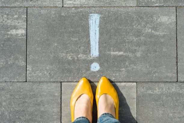 Female feet with exclamation point, symbol of attention drawn on the asphalt stock photo