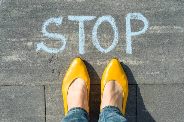 istock Female feet with text stop written on asphalt 959324582