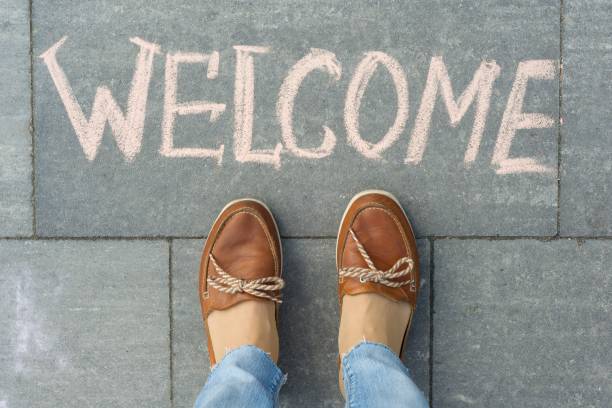 istock Female feet with text welcome written on grey sidewalk 959324868