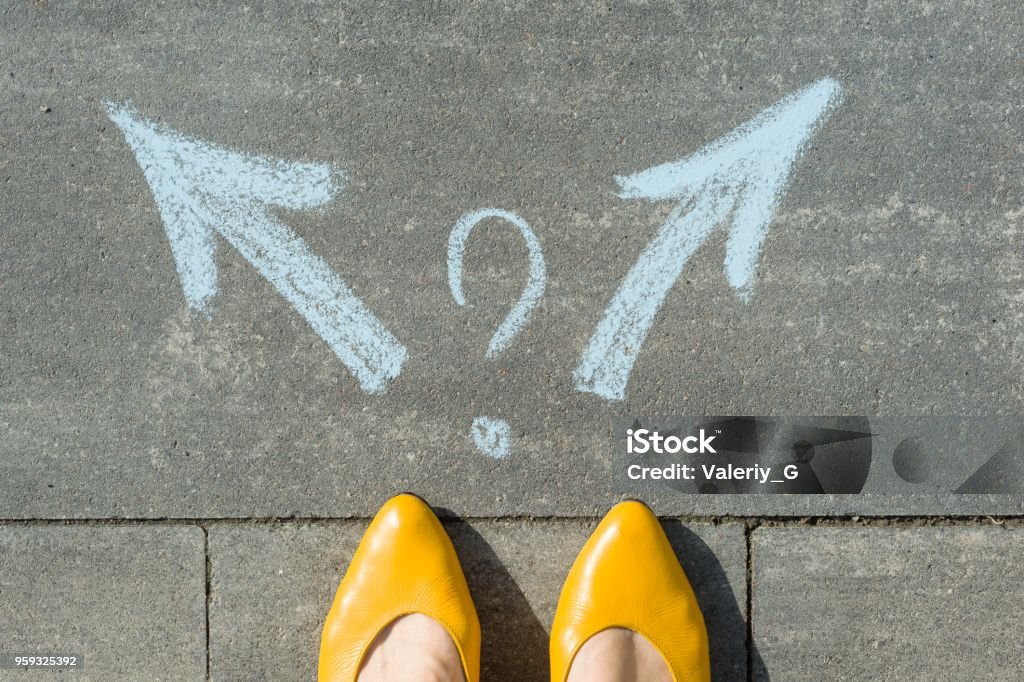 Female legs with 2 arrows and question mark, painted on the asphalt Female legs with 2 arrows and question mark, painted on the asphalt. Choice Stock Photo