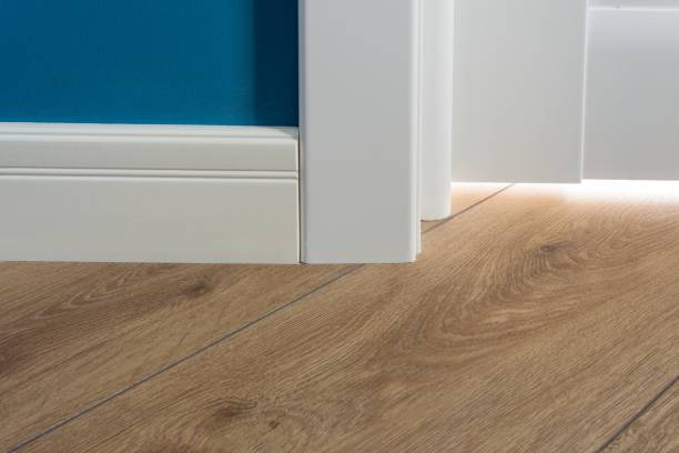 istock Details in the interior. Laminated parquet floors immitating oak texture, white baseboard, white door. 959327624
