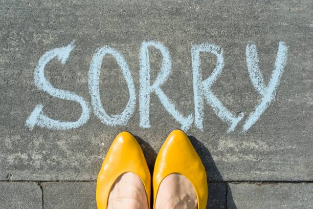 istock Female feet with text sorry written on asphalt. 959328294
