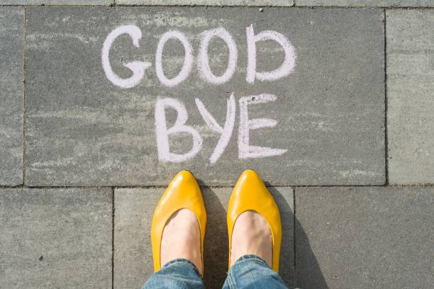 Female feet with text goodbye written on asphalt