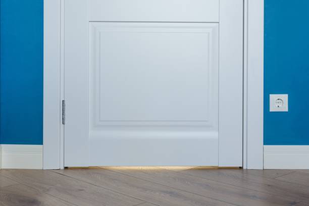 istock Details in the interior. Laminated parquet floors immitating oak texture, white baseboard, white door. 959328664