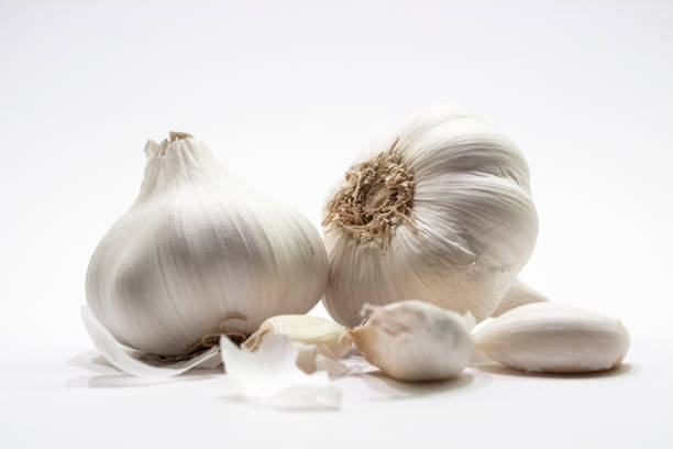 garlic-on-white-crushed-front two garlic bulbs with skin peeled off and seperate carlic clove on white background garlic bulb stock pictures, royalty-free photos & images