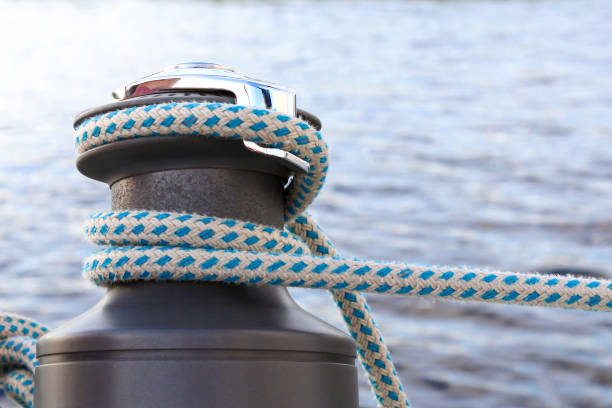 istock Beautiful shiny black bitt with a blue mooring cable rope on blue water background 959332262