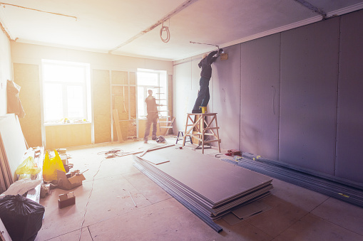 Los trabajadores a instalar placas de yeso (drywall) para paredes de yeso en apartamento está en construcción, remodelación, restauración, ampliación, restauración y reconstrucción. photo