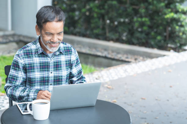 istock Smiling attractive mature man with white, grey stylish short beard using smartphone gadget serving internet in modern office,co-working space or coffee shop. Old man using social network technology. 959336408