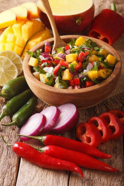 istock Salsa with mango, cilantro, onions and peppers close up and ingredients on the table. vertical 959350760