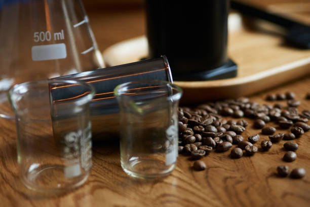 Coffee beans and glassware for coffee preparing on wooden table, close-up
