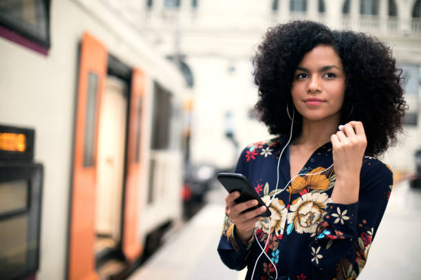 istock Smiling woman using phone at train station 959362460