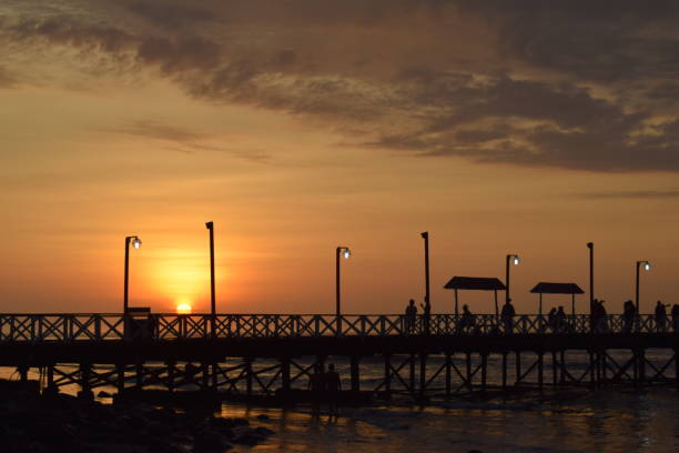 солнце прячется за пирсом хуанчако в перу - huanchaco стоковые фото и изображения