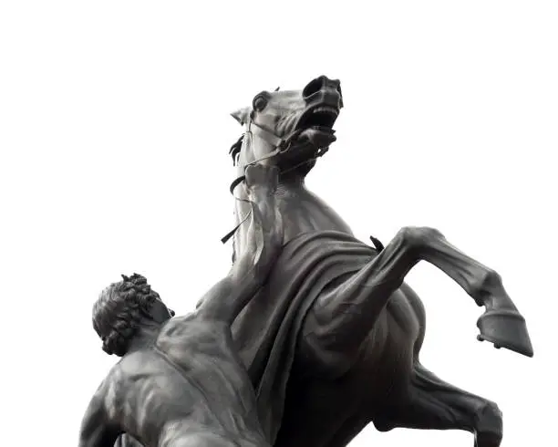 Photo of Sculpture of the ancient man holding a mad horse isolated on white backgound