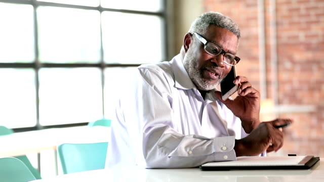 Senior African-American businessman on phone takes notes