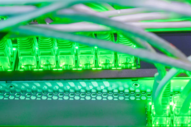 多くのネットワーク回線は、管理スイッチに接続されます。インターネット接続の明るい緑の表示。ケーブルの多くは、ネットワークのルーターのインターフェイスに含まれます。 - cable network server network connection plug green ストックフォトと画像