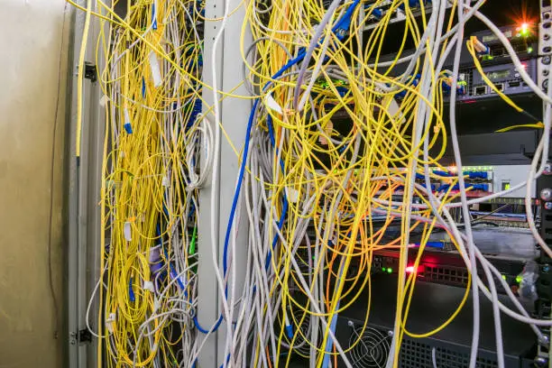 Entangled Internet wires are in the server room. Disorderly connection of optical cables with computer equipment. Racks with servers are located in the datacenter