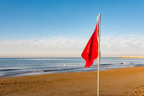 istock Red flag and empty sandy beach and sea in sunrise 959368916