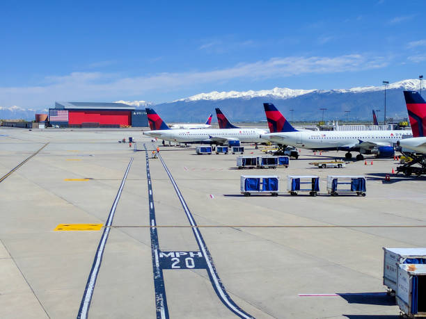 Delta Airlines airplanes lined up at the gates at Salt Lake City airport (SLC) on a beautiful spring day. The mountains in the background are snow capped.