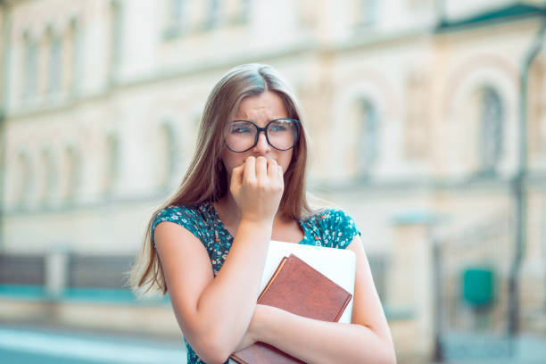 studentessa stressata giovane donna mordere le unghie distogliendo lo sguardo con ansia - nuerotic foto e immagini stock