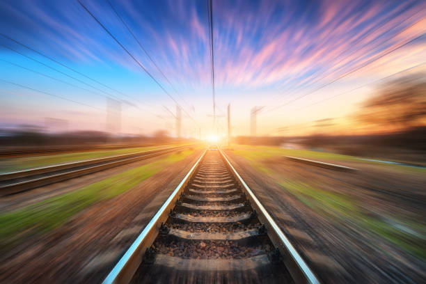 Railway station with motion blur effect at sunset. Blurred railroad. Industrial conceptual landscape with blurred railway station, blue sky with pink clouds and sunlight. Railway track in summer Railway station with motion blur effect at sunset. Blurred railroad. Industrial conceptual landscape with blurred railway station, blue sky with pink clouds and sunlight. Railway track in summer railroad track stock pictures, royalty-free photos & images