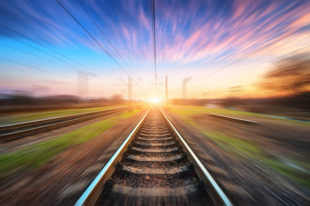 Railway station with motion blur effect at sunset. Blurred railroad. Industrial conceptual landscape with blurred railway station, blue sky with pink clouds and sunlight. Railway track in summer Railway station with motion blur effect at sunset. Blurred railroad. Industrial conceptual landscape with blurred railway station, blue sky with pink clouds and sunlight. Railway track in summer railway track stock pictures, royalty-free photos & images