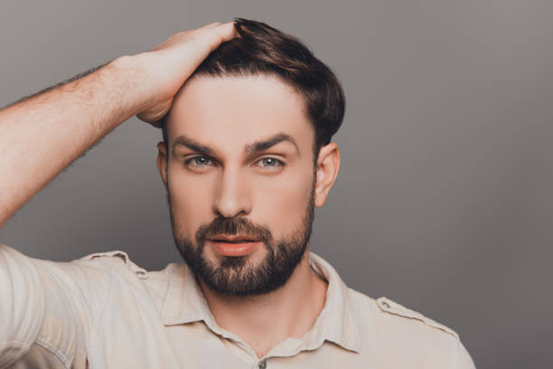 istock Attractive man touching his hair on gray background 959376812