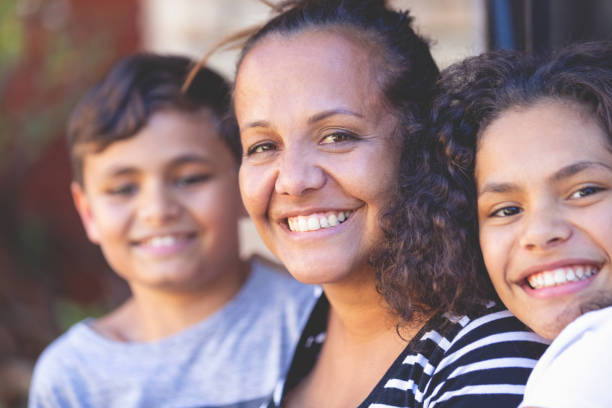 Aboriginal Family portrait with 1 parent and 2 children. Aboriginal Family portrait with 1 parent and 2 children. They are sitting on the front porch. Everyone is happy and smiling. Could be a single mother. australian culture stock pictures, royalty-free photos & images