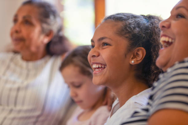 Multi generational women on the sofa. The young girls are sisters. Multi generational women on the sofa. The young girls are sisters. One is a teenager on is younger. There is also a mother and grandmother. They are all happy and smiling. They are all  Australian Aboriginals. indegious culture stock pictures, royalty-free photos & images