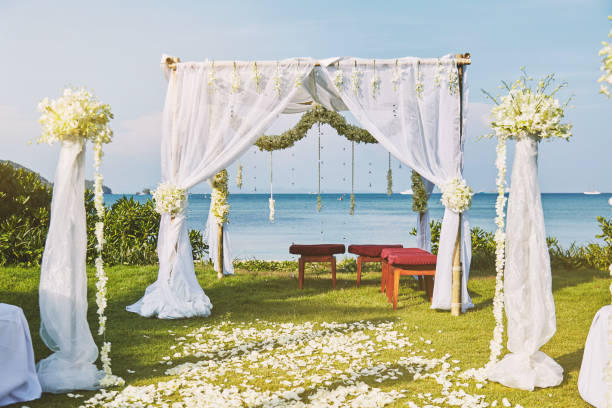 Beautiful beach wedding flower arch setting for wedding venue with panoramic ocean view The beautiful wedding venue setting with flowers, floral decoration on arch with panoramic ocean view in background altar photos stock pictures, royalty-free photos & images