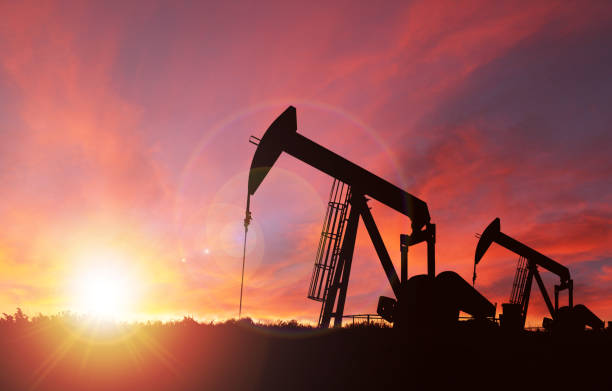 Sunset Over Pumpjack Silhouette With Copy Space Pump jack silhouette against a sunset sky with deliberate lens flare and copy space. These jacks can extract between 5 to 40 litres of crude oil and water emulsion at each stroke.  

This image is made up of 2 photos attached here for reference--one is my image of an Alberta landscape sunset shot in Calgary; the other is my photo of a pump jack shot in rural Alberta and then converted into a silhouette before compositing them together in Photoshop. oil well stock pictures, royalty-free photos & images