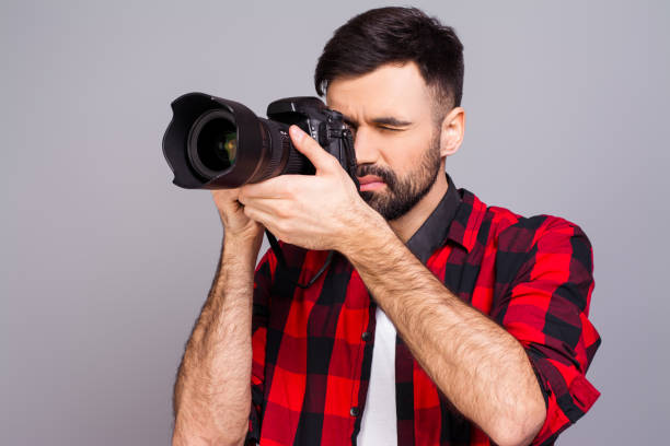 istock Handsome young man photographing you on gray background 959385360