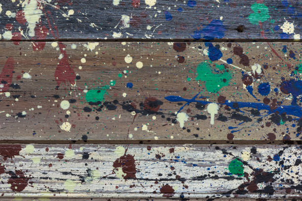 istock Multicolored abstract paint splatters on weathered wooden boards. 959385586