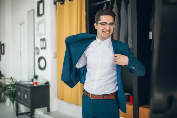 Young handsome man in boutique choosing tuxedo