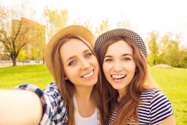 istock Two cheerful smiling sisters making selfie and showing tongue 959395352