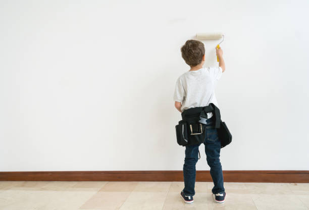 Happy boy painting a wall with a paintbrush - interior design concepts